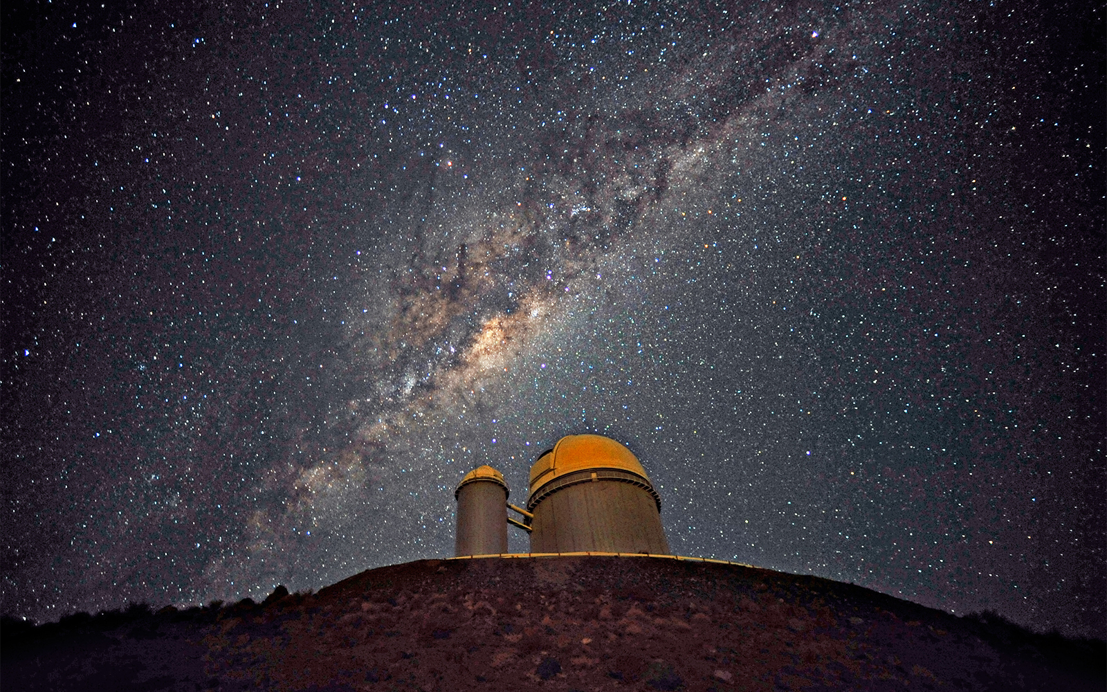The Milky Way Galaxy is seen across the night skt over a domed telescope.