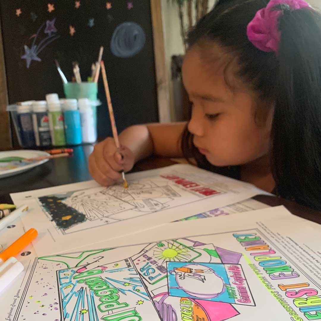 A young girl paints Exoplanet Coloring Book pages.